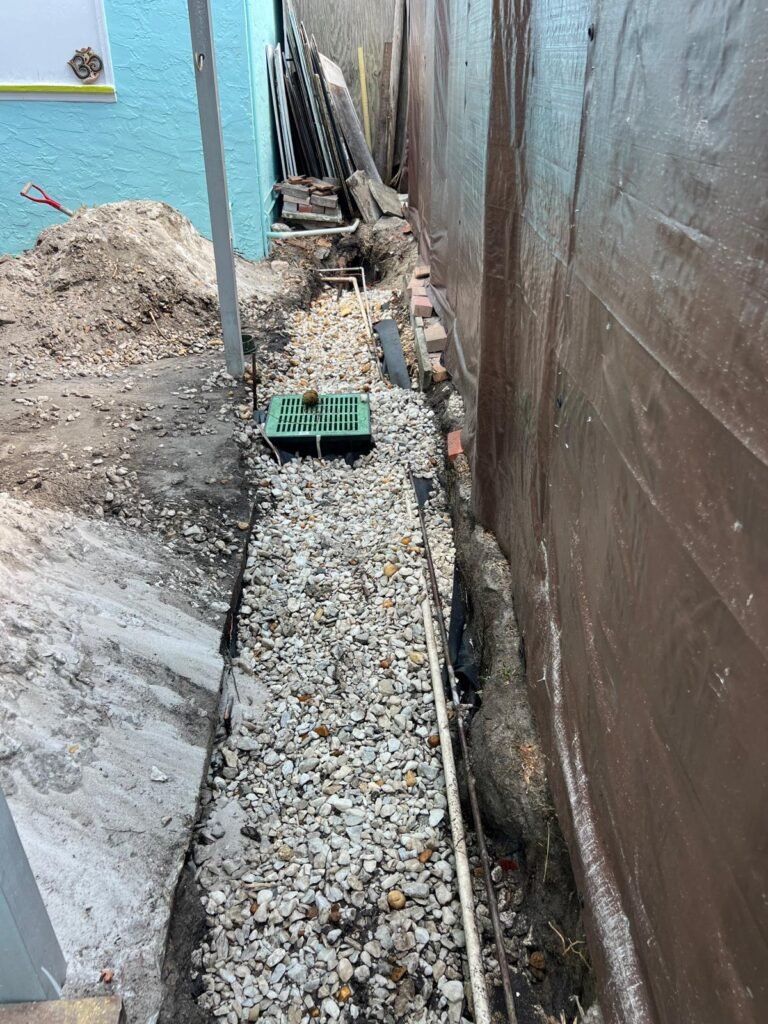 Gravel French drain running along a side yard wall