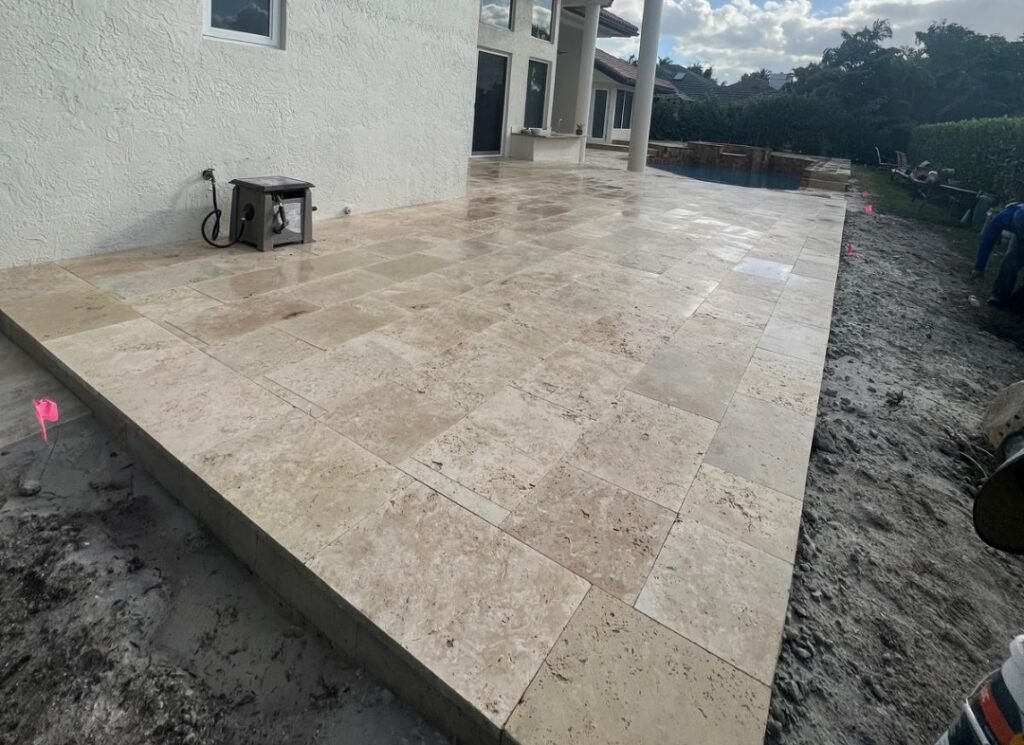 Ivory travertine patio freshly laid along the back of a home