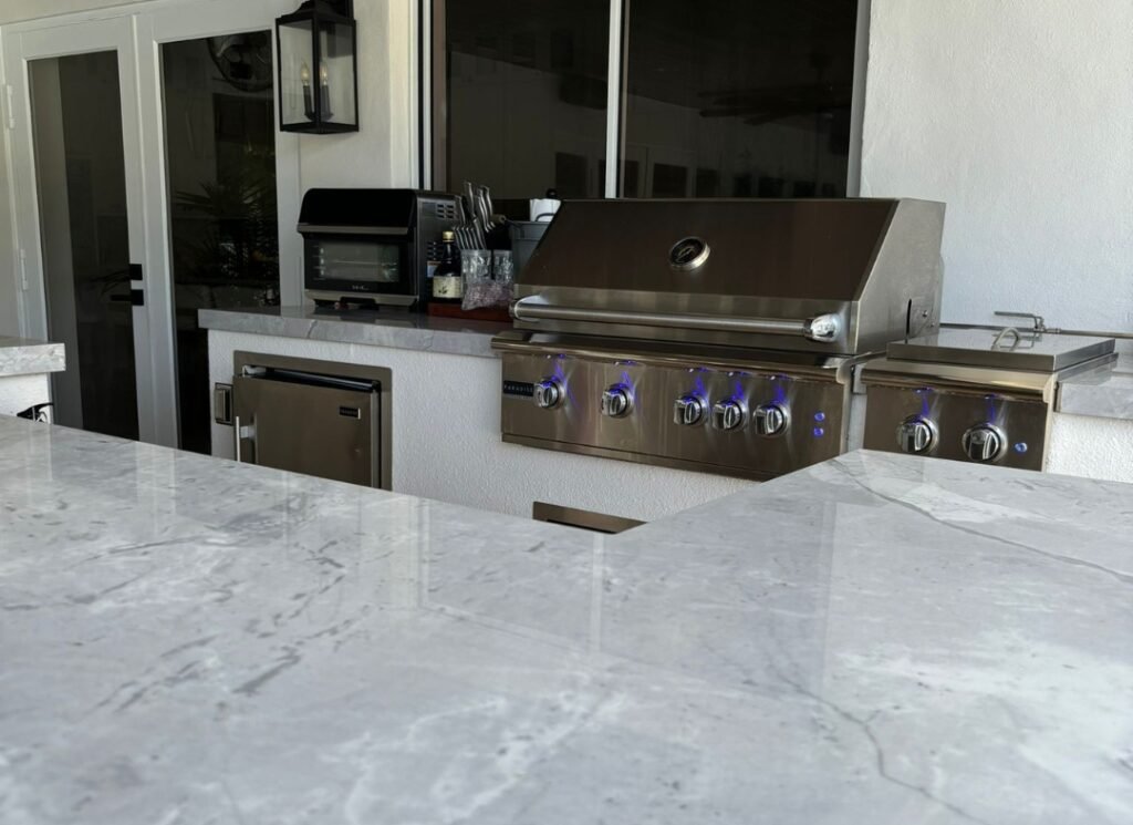 Marble countertop and built-in grill in a covered outdoor kitchen