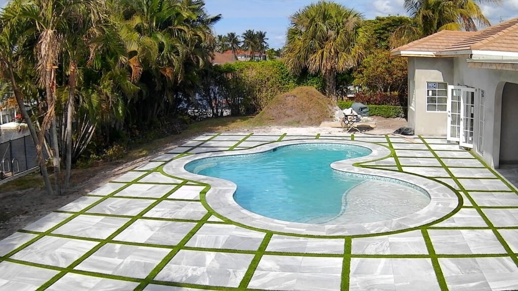 Pavers in Delray Beach, FL: white pavers with grass joints around a pool, from a Hero’s Pavers job elsewhere in Palm Beach County