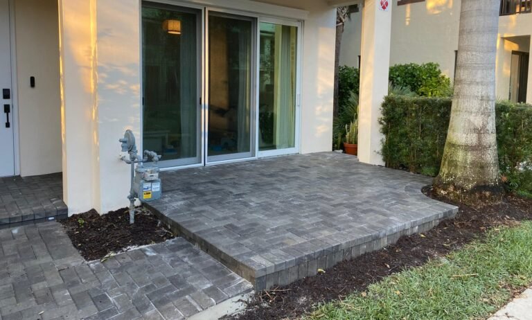 Raised gray paver patio and walkway at a townhome front entry