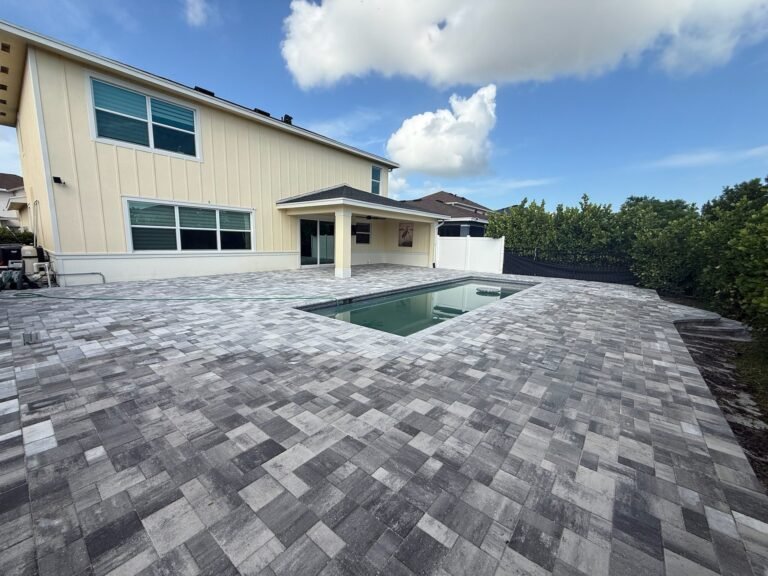 Gray blend paver pool deck around a rectangular pool behind a new home