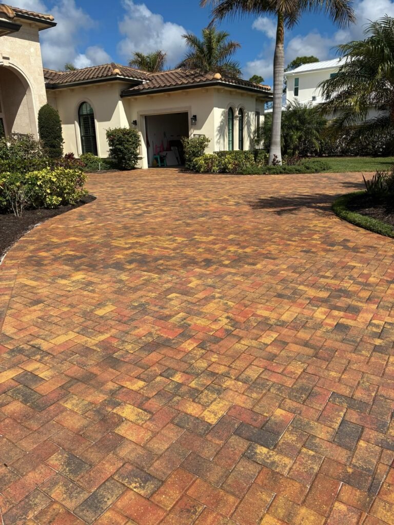 Curved tumbled paver driveway in warm red and gold tones at a Mediterranean-style home