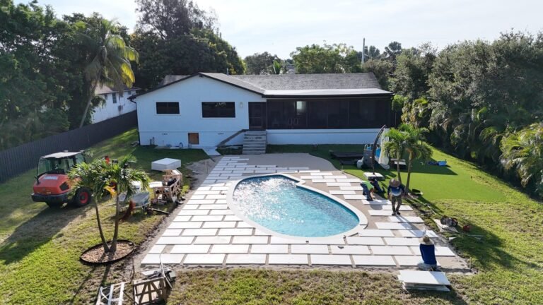 Drone view of Hero's Pavers crew laying white pavers around a pool in Boynton Beach, FL