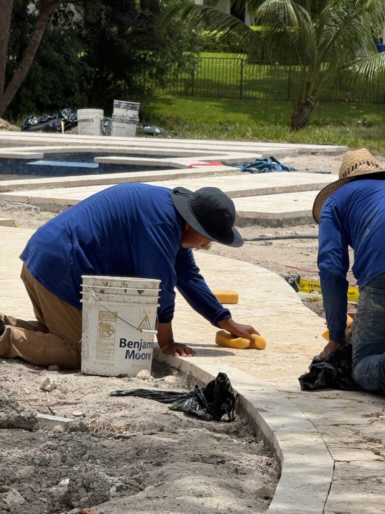 Hero's Pavers installers setting a curved travertine walkway by hand