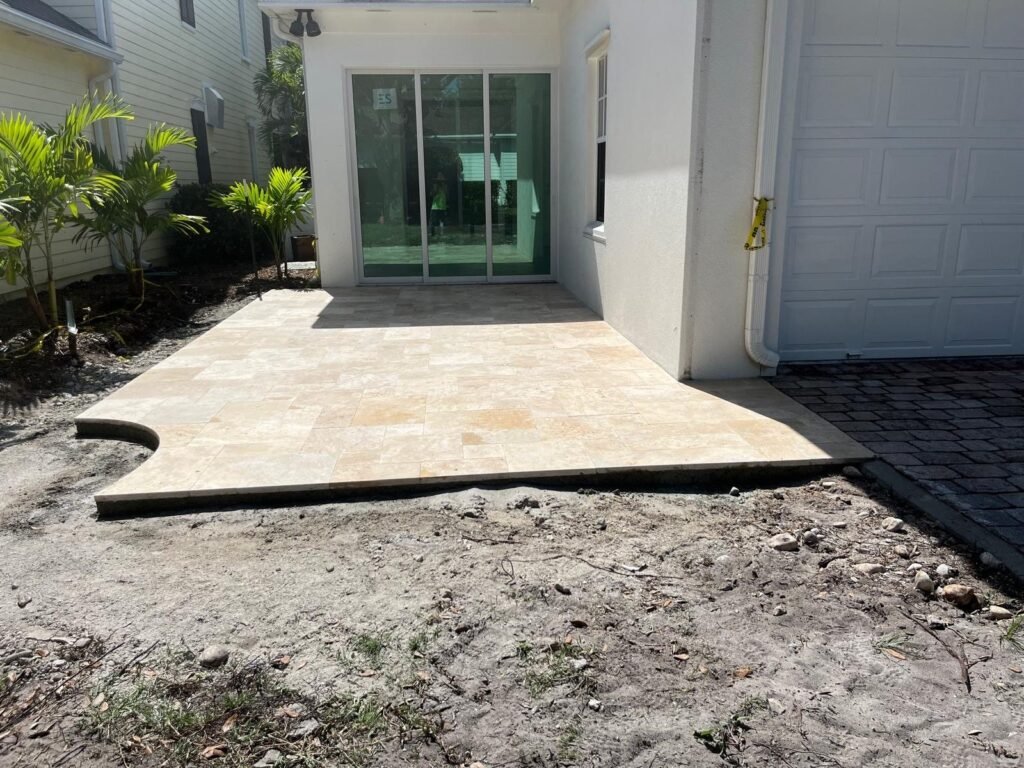 New travertine patio with a curved edge outside a sliding glass door