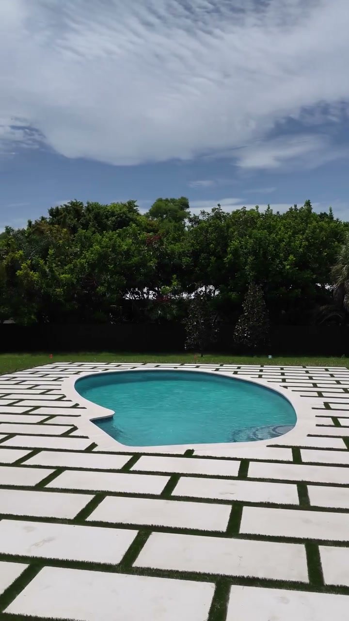 Kidney-shaped pool framed by white pavers set in an artificial turf grid, Boynton Beach, FL